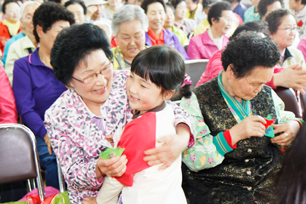 지난 7일 열린 어버이날 기념식에서 목화어린이집 한 어린이가 어르신에게 선물을 안겨드리며 활짝 웃고 있다.