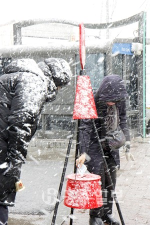 연말을 맞아 사랑의 종소리를 울리며 불우이웃 돕기 자선모금운동을 펼치는 '구세군 자선냄비'가 등장해 행인들의 시선을 사로잡고 있다. 올해는 지난 5일부터 홍성읍 명동상가, 광천오거리 등에서 자선모금운동이 펼쳐지고 있다. 사진은 세찬 눈이 내리는 지난 11일 광천오거리에 설치된 구세군 자선냄비에 성금을 넣고 있는 행인의 모습.