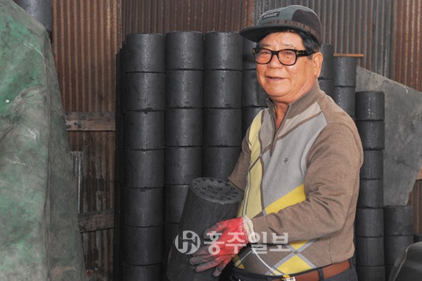 오랜 친구와도 같은 연탄을 들어보이고 있는 김관식 대표.