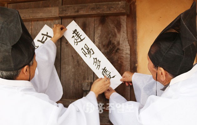 구항면 거북이마을은 지난 4일 입춘을 맞아 입춘첩을 마을회관 등에 붙이며 봄을 반겼다. 사진은 방규석(85) 어르신과 전영수(72) 마당놀이총감독이 마을 내 약천초당에 입춘대길 건양다경이라고 쓴 입춘첩을 붙이고 있는 모습.