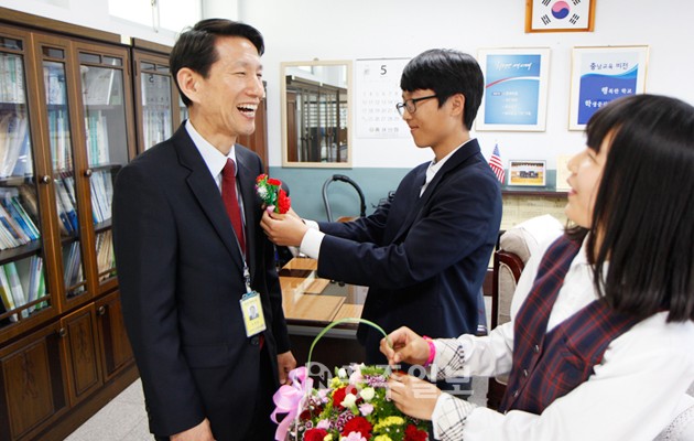 스승의 날을 맞아 갈산중학교 전종현 교장에게 3학년 박철순 학생과 김서현 학생이 카네이션을 달아주고 있다.