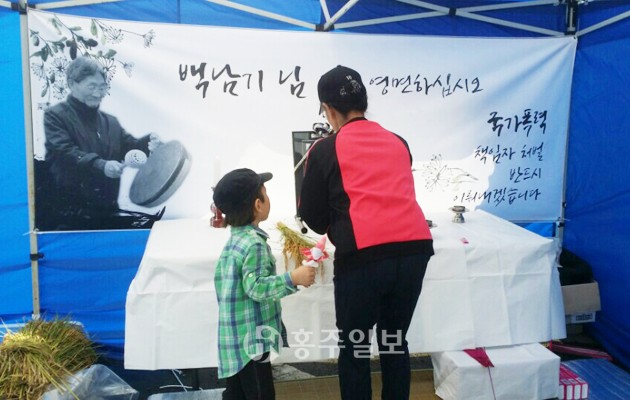 지난 해 11월 쌀값 보장을 외치며 집회에 참석했다 경찰의 물대포에 맞아 317일 동안 의식불명 상태로 투병생활을 해왔던 백남기 농민이 지난 달 25일 운명했다. 이에 지난 5일 백남기 농민의 뜻을 기리고 추모하기 위한 분향소가 홍성읍 복개주차장에 마련됐다. 홍성군 시민사회단체가 마련한 분향소는 아침 8시부터 저녁 10시까지 조문객을 맞는다. 시민사회단체 관계자는 민주주의와 정의를 사랑하는 홍성군민의 조문을 당부하며, 뜻있는 단체들의 합류를 부탁했다.