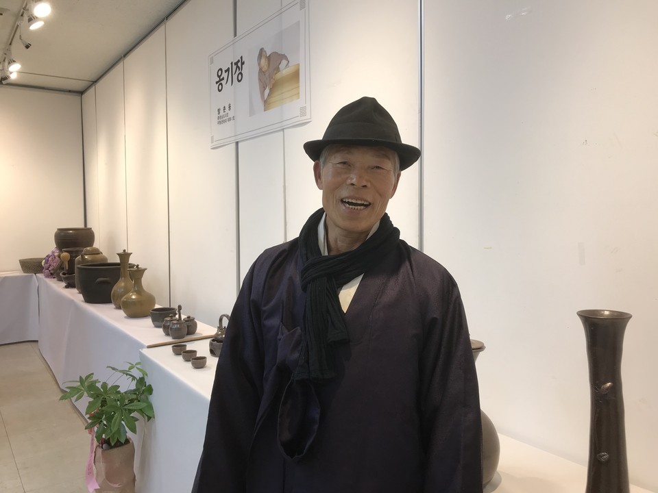 옹기장 방춘웅 씨가 출품한 자신의 작품들 앞에서 관람객들을 향해 환하게 웃고 있다.