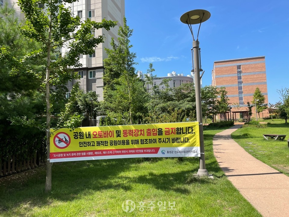 녹지 공간 내 이륜차의 불법출입 제한을 알리는 현수막.