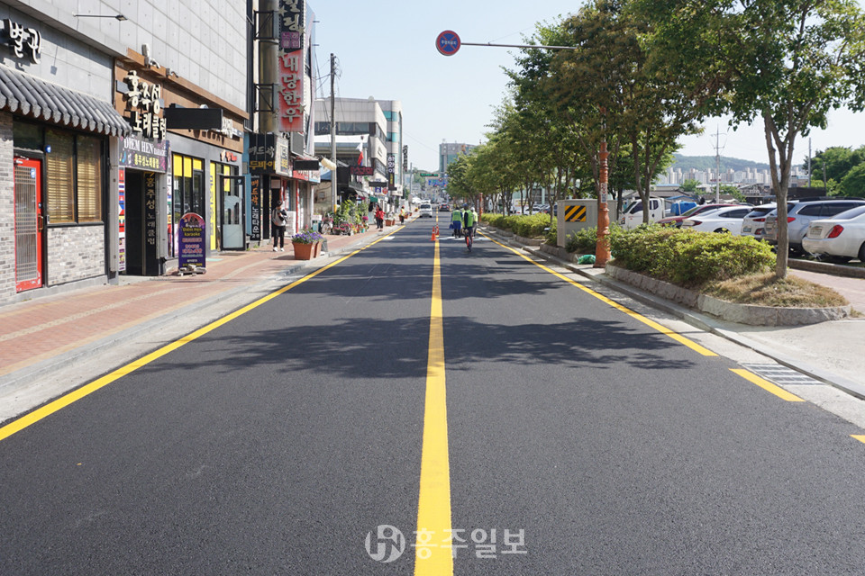 지난 23일 아스콘 포장을 마치고 차선도색 작업 중인 도로.<br>