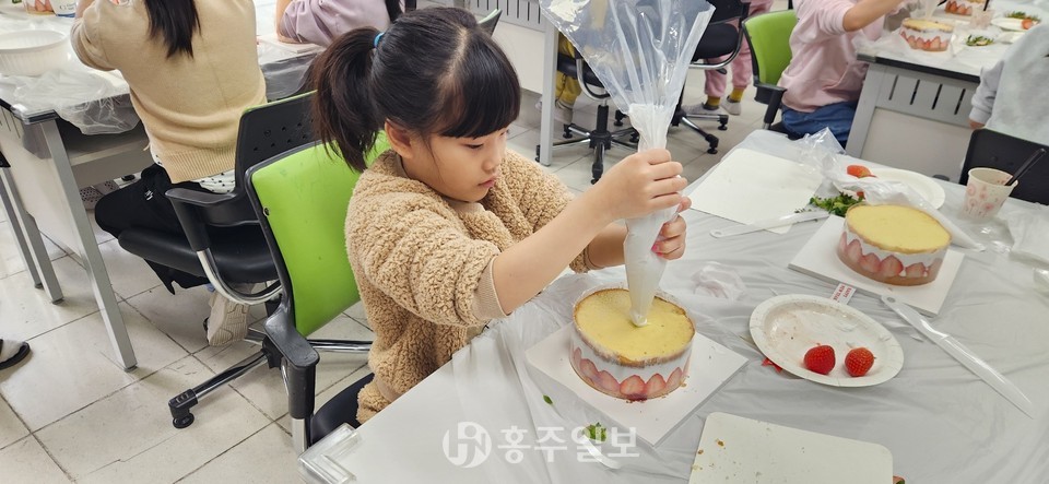 체험에 참여한 한 학생이 생크림 짤 주머니를 들고 데코레이션에 집중한 모습이다.
