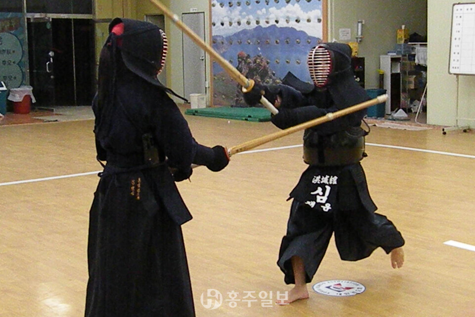 검도관에서 회원들이 활기찬 함성과 함께 운동을 하고 있다.